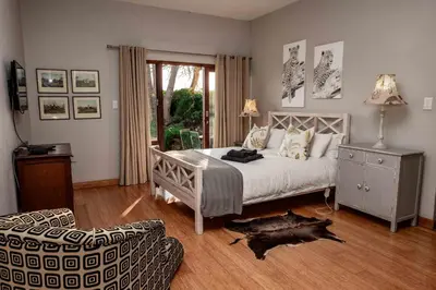 a bedroom with a bed and a chair and a table at 10onBrightside-Exp the epitome of country living in Nelspruit