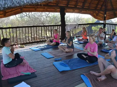 a group of people sitting on a deck doing yoga at Simunye Private Game Reserve in Brits
