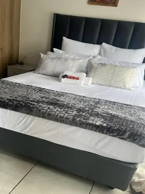a large bed with white sheets and pillows at Cozy Pretoria Apartment with City Garden Views in Pretoria