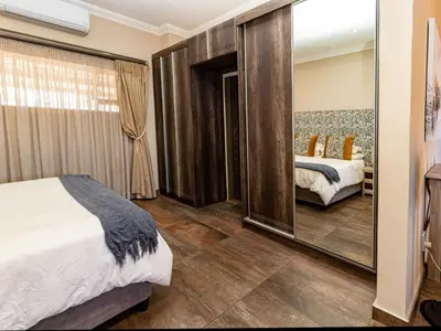 a bedroom with a mirror and a bed in a room at Somethin Special Guest House 77A in Mokopane