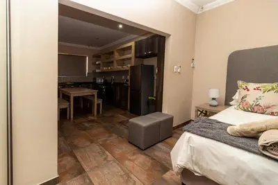 a bedroom with a bed and a kitchen with a table at Somethin Special Guest House 77A in Mokopane