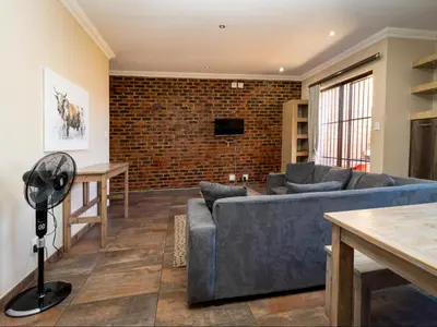 a living room with a blue couch and a brick wall at Somethin Special Guest House 77A in Mokopane