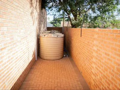 a brick wall with a water tank next to a fence at Somethin Special Guest House 77A in Mokopane