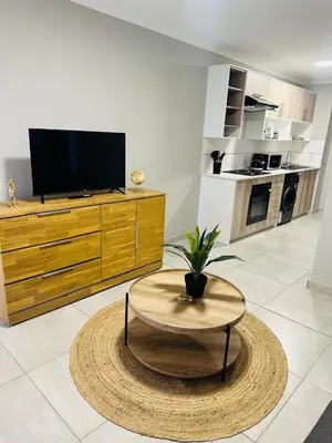 a living room with a table and a tv at Homely Stay 4 in Kempton Park