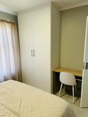 a bedroom with a bed and a desk and a chair at Homely Stay 4 in Kempton Park