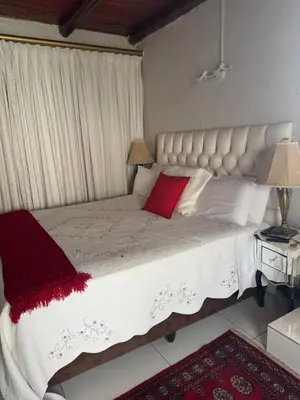 a bedroom with a large white bed with red pillows at Secret Place in Pretoria