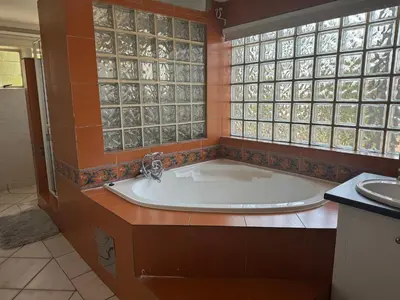 a bath tub in a bathroom with glass windows at Secret Place in Pretoria