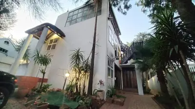 a white house with palm trees in front of it at Secret Place in Pretoria