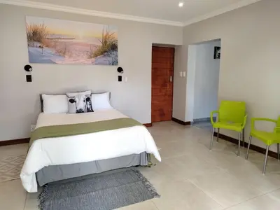 a bedroom with a bed and two green chairs at Grace 523 in Pretoria