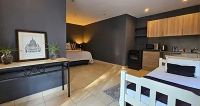 a bedroom with a bed and a kitchen in a room at Belle Vie Boutique Guesthouse in Pretoria