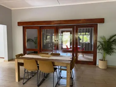 a dining room with a wooden table and chairs at Emoyeni Malelane Lodge in Malelane