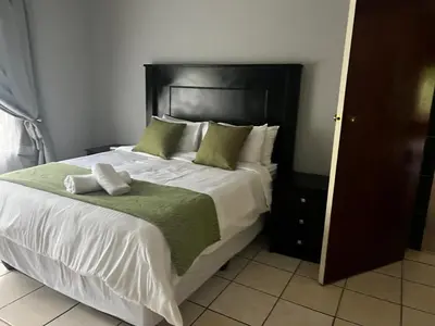 a bedroom with a large white bed with green pillows at Emoyeni Malelane Lodge in Malelane