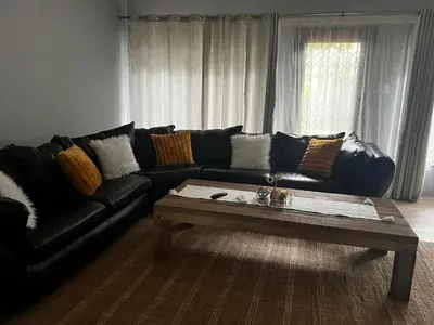 a living room with a black couch and a coffee table at Emoyeni Malelane Lodge in Malelane