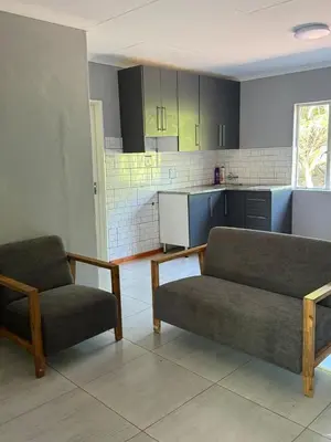 a living room with two couches and a kitchen at Emoyeni Malelane Lodge in Malelane