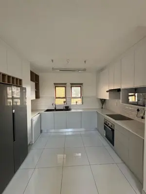a white kitchen with white cabinets and appliances at Home away from Home in Midrand