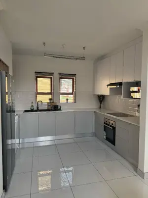 a large white kitchen with white cabinets and appliances at Home away from Home in Midrand