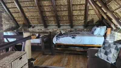 a bedroom with two beds in a thatched room at Parradys Marloth Park in Marloth Park