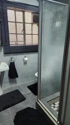 a bathroom with a glass shower and a sink at Parradys Marloth Park in Marloth Park