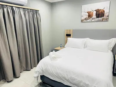 a bedroom with a large white bed and curtains at Ngwede Guest House in Lydenburg