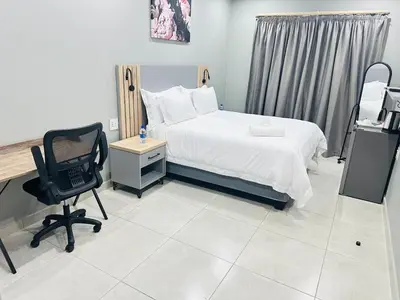 a bedroom with a bed and a desk and a chair at Ngwede Guest House in Lydenburg