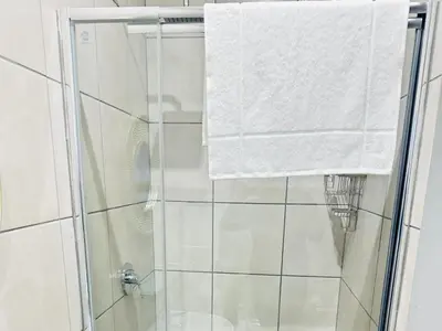 a shower with a glass door and a towel at Ngwede Guest House in Lydenburg