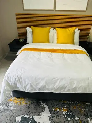 a bedroom with a large bed with yellow pillows at Impèrio Boutique Guest Lodge in Siyabuswa
