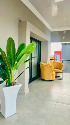 a living room with a potted plant and yellow chairs at Impèrio Boutique Guest Lodge in Siyabuswa