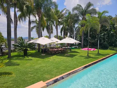 a resort yard with tables and umbrellas and a pool at The Embassy in Pretoria