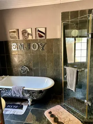 a bathroom with a tub and a glass shower at Villa Afriq in Lydenburg