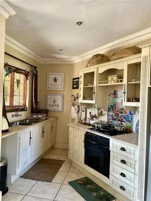 a kitchen with white cabinets and a black dishwasher at Villa Afriq in Lydenburg