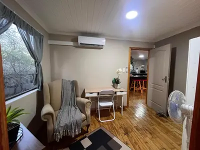 a living room with chairs and a table with a fan at Erdvarkie at Kruger, Marloth Park in Marloth Park