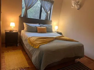 a bedroom with a bed with two lamps and a window at Erdvarkie at Kruger, Marloth Park in Marloth Park