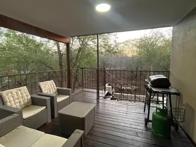 a screened porch with couches and chairs on a deck at Erdvarkie at Kruger, Marloth Park in Marloth Park