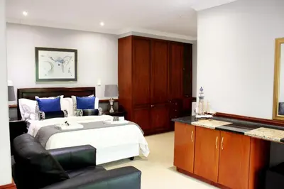 a bedroom with a king sized bed and a couch at Prinshof Manor Guesthouse in Pretoria