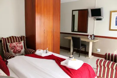 a hotel room with a bed and a table at Prinshof Manor Guesthouse in Pretoria