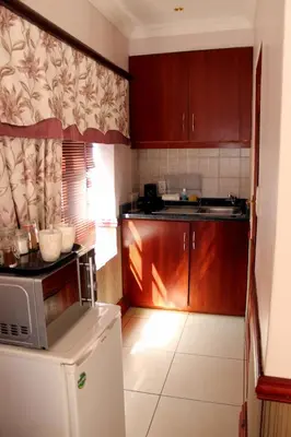 a kitchen with wooden cabinets and a white refrigerator at Prinshof Manor Guesthouse in Pretoria