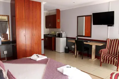a room with a kitchen with a table and a desk at Prinshof Manor Guesthouse in Pretoria