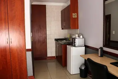a small kitchen with a white refrigerator and a table at Prinshof Manor Guesthouse in Pretoria