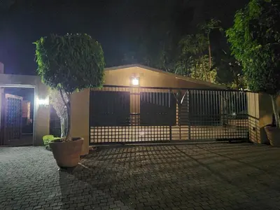 a house with a fence and a tree in front of it at Lazy Trail Cottage in Nelspruit