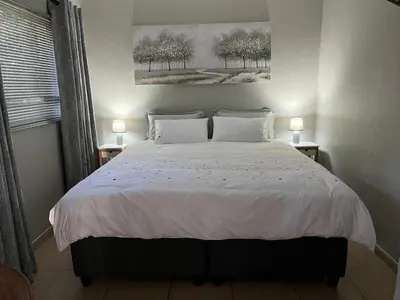 a bedroom with a large bed with two lamps at Lazy Trail Cottage in Nelspruit
