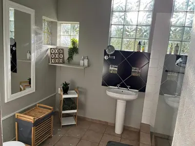 a bathroom with a sink and a toilet and windows at Lazy Trail Cottage in Nelspruit