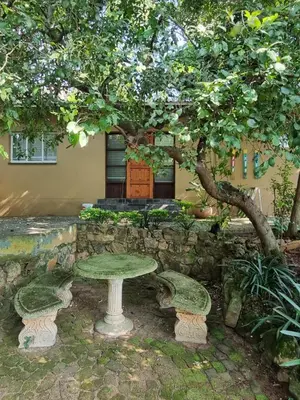 a stone table and benches under a tree at Lazy Trail Cottage in Nelspruit