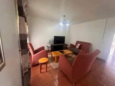 a living room with two chairs and a television at The Lake Villa 2 in Benoni
