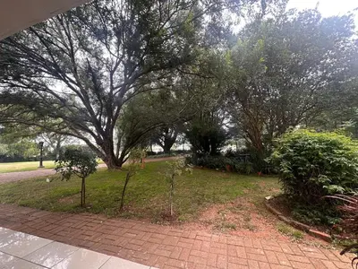 a park with a large tree and a brick walkway at The Lake Villa 2 in Benoni