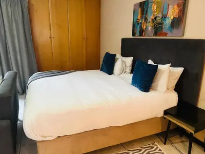 a bedroom with a large white bed with blue pillows at Mbizo Cozy Retreat- Lofts at Loftus in Pretoria