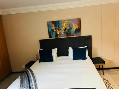 a bedroom with a large bed with blue pillows at Mbizo Cozy Retreat- Lofts at Loftus in Pretoria