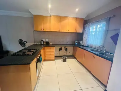 a small kitchen with wooden cabinets and a sink at Mbizo Cozy Retreat- Lofts at Loftus in Pretoria