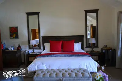 a bedroom with a large bed with red pillows at Lakeside 1 in Dullstroom