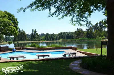 a swimming pool with picnic tables and a lake at Lakeside 1 in Dullstroom