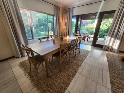 a dining room with a long wooden table and chairs at Maclarty House - Golf Estate Villa in White River